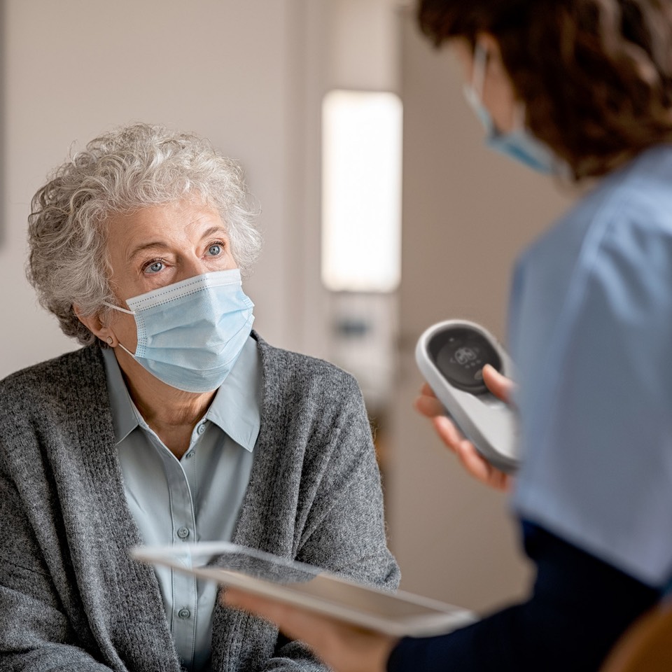 senior patient and nurse holding a pyxy device and a tablet computer.